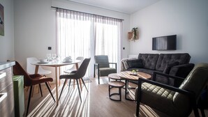 A modern living room with a sofa, dining table, chairs, and a flat-screen TV. - Ferienwohnungen mit Skilift Direkt am Haus (Winterberg)
