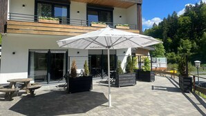 A modern building with a patio area, outdoor seating, and a sign for a pizza restaurant. - Ferienwohnungen mit Skilift Direkt am Haus (Winterberg)