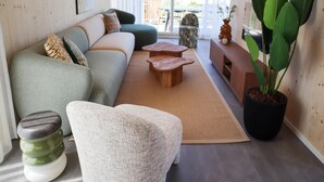 A modern living room with a sofa, coffee table, and potted plants. - 4-bedroom Stylish Bungalow by the Sea ('s-Gravenzande)