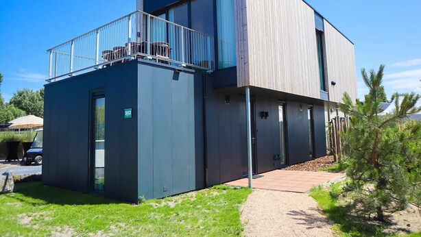 A modern two-story building with a balcony, a door labeled '302', and a gravel path leading to the entrance. - 4-bedroom Stylish Bungalow by the Sea ('s-Gravenzande)