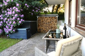 Um pátio com mesa, cadeiras, lareira e uma pilha de lenha.