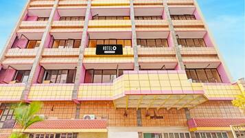 Un hotel de varios pisos con un llamativo letrero que dice 'HOTEL', balcones y fachada de azulejos.