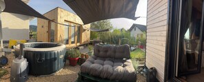 Une cabane en bois dotée d’un bain à remous, d’un coin salon confortable et donnant sur un jardin.