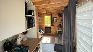A compact, wooden interior with a kitchenette, a dining area, and a bed. - Brand new equipped garden studio in a beautiful region near mountains and lake (Perrignier)