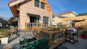 A wooden house with a deck, outdoor furniture, and a barbecue area. - Brand new equipped garden studio in a beautiful region near mountains and lake (Perrignier)