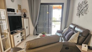 A living room with a sofa, TV, and a table with a plant. - Casa Del Sol Rio in Costa Calma (Costa Calma)