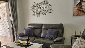 A living room with a brown leather sofa, a white coffee table, and a decorative metal wall piece. - Casa Del Sol Rio in Costa Calma (Costa Calma)