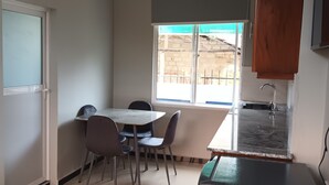 Eine Küche mit Kühlschrank, einem Esstisch mit Stühlen, einem Fenster mit Blick und einem Deckenventilator.