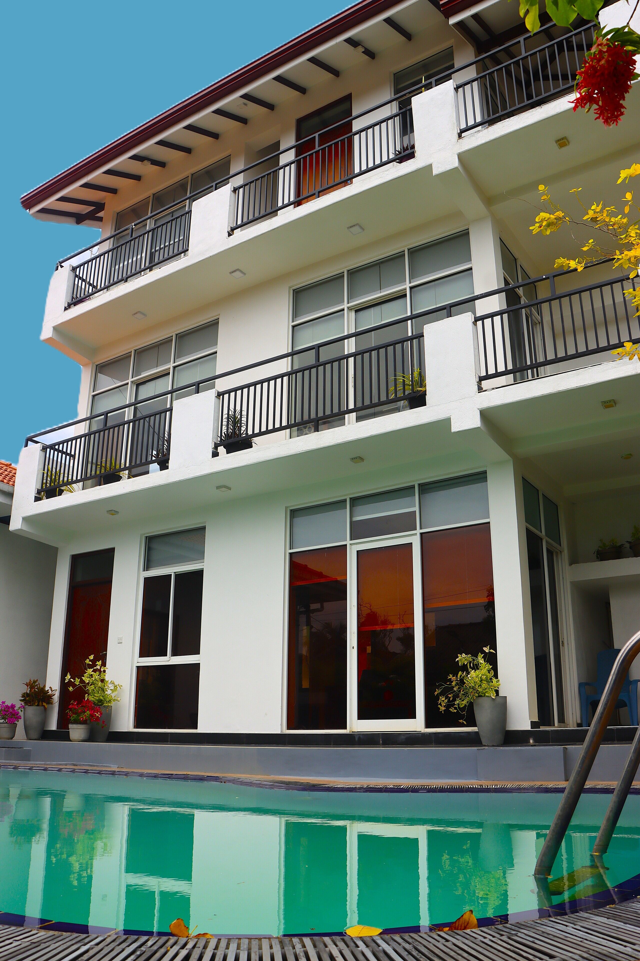 A multi-story building with balconies, a swimming pool, and potted plants.