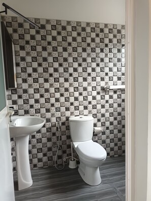 A bathroom with a checkered tile wall, a white sink, and a toilet.