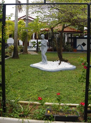 A garden with a statue, a lawn, and a building in the background. - The Kumatha Residence, Ground Floor one bedroom  Studio apartment , pool view (Negombo)