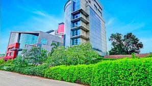 A modern building with a curved facade, multiple floors, and a mix of glass and concrete materials. - Deluxe With Twin Bed Sitabuldi Station (Nagpur)
