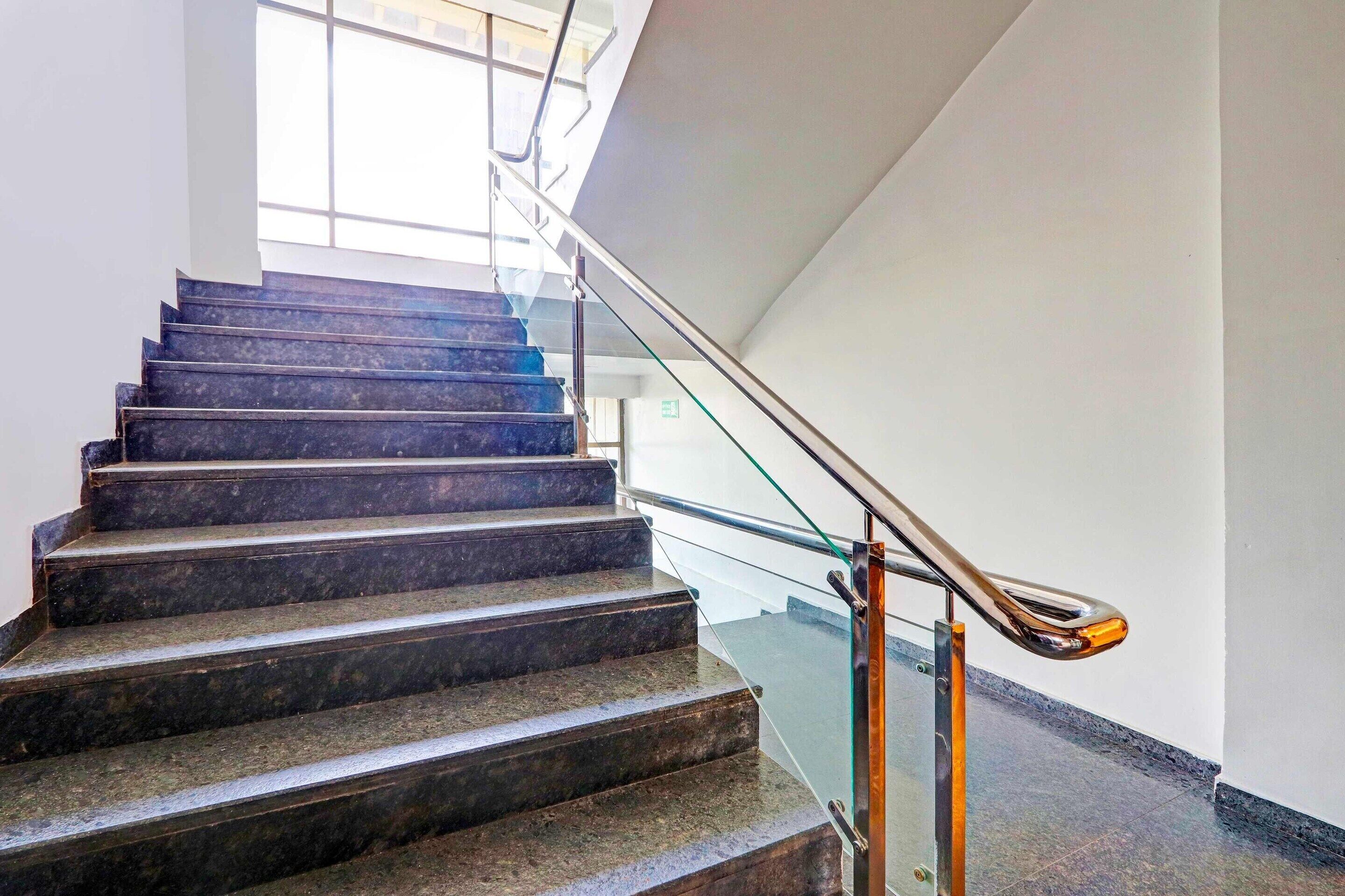 A staircase with dark steps and a glass railing.