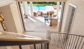 A view from a balcony to a pool area with outdoor seating and a view of the pool. - Villa Tamarindo - by ZenBreak (Holetown)