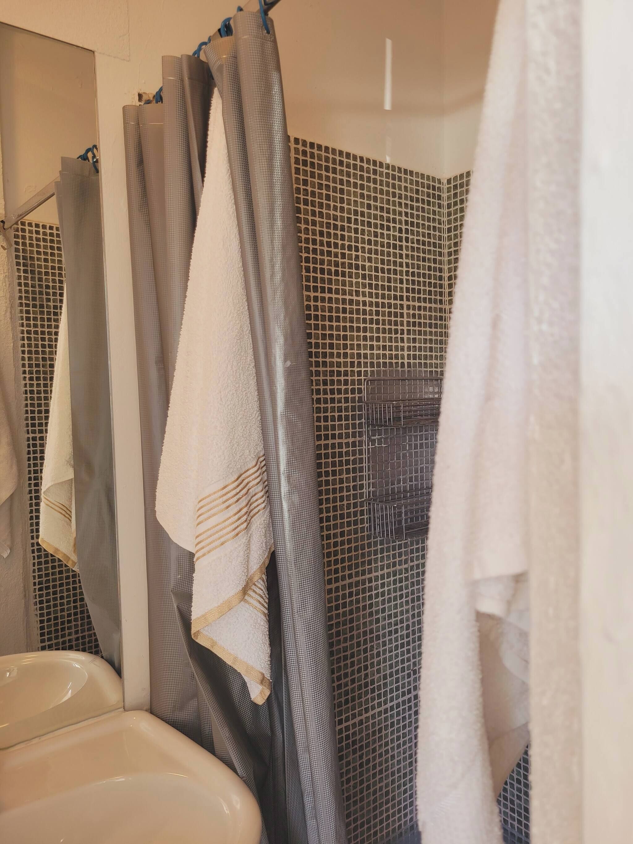 Un bagno con lavandino, specchio e zona doccia con tenda.