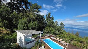 Ein Pool auf dem Dach mit Liegestühlen, einer kleinen Terrasse und Blick auf das Meer.