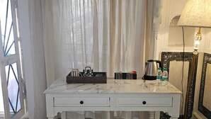 A white marble table with a tray, a coffee maker, and a lamp in a room with a stained glass window and a door. - Experience Royal Living in a Heritage Haveli (Jaipur)
