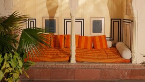 A traditional room with a bed, a potted plant, and a decorative ceiling. - Experience Royal Living in a Heritage Haveli (Jaipur)