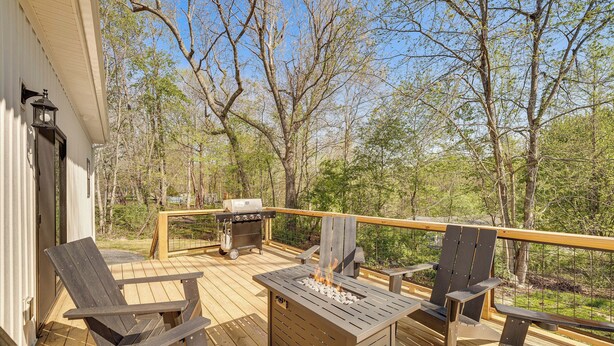Une terrasse avec des chaises en bois, un barbecue et un foyer extérieur.