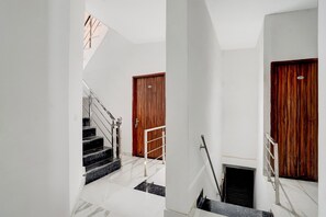 Un escalier avec une rampe, une porte en bois et un portail en métal.