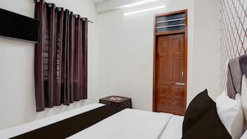 A bedroom with a bed, curtains, a wooden door, and a small table.