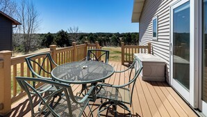 A deck with a table and chairs, a sliding glass door, and a view of the surrounding landscape. - < 1 Mi to Calamus Lake! Group Adventure Base (Burwell)