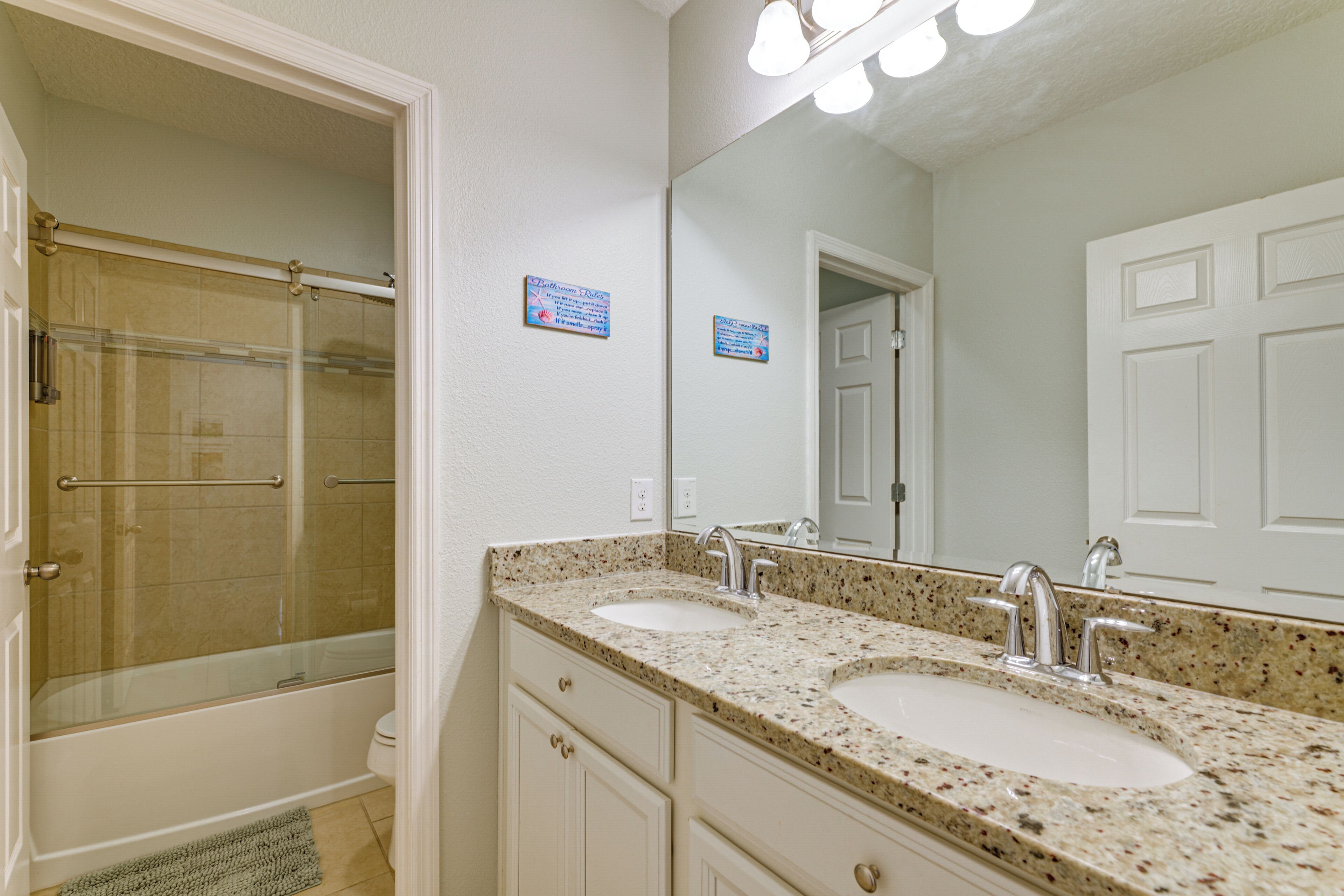 A bathroom with two sinks, a shower, and a mirror.