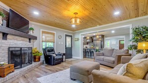 A living room with a fireplace, leather chair, ottoman, and a sofa. - Covered Patio, Fire Pit & Grills: Olmstead Getaway (Olmstead)