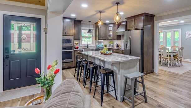 A modern kitchen with a central island, bar stools, and pendant lighting. - Covered Patio, Fire Pit & Grills: Olmstead Getaway (Olmstead)
