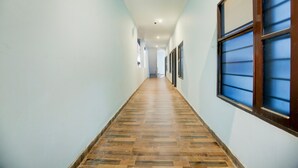Ein Flur mit Holzboden, hellblauen Wänden und einem Fenster mit blauen Jalousien.