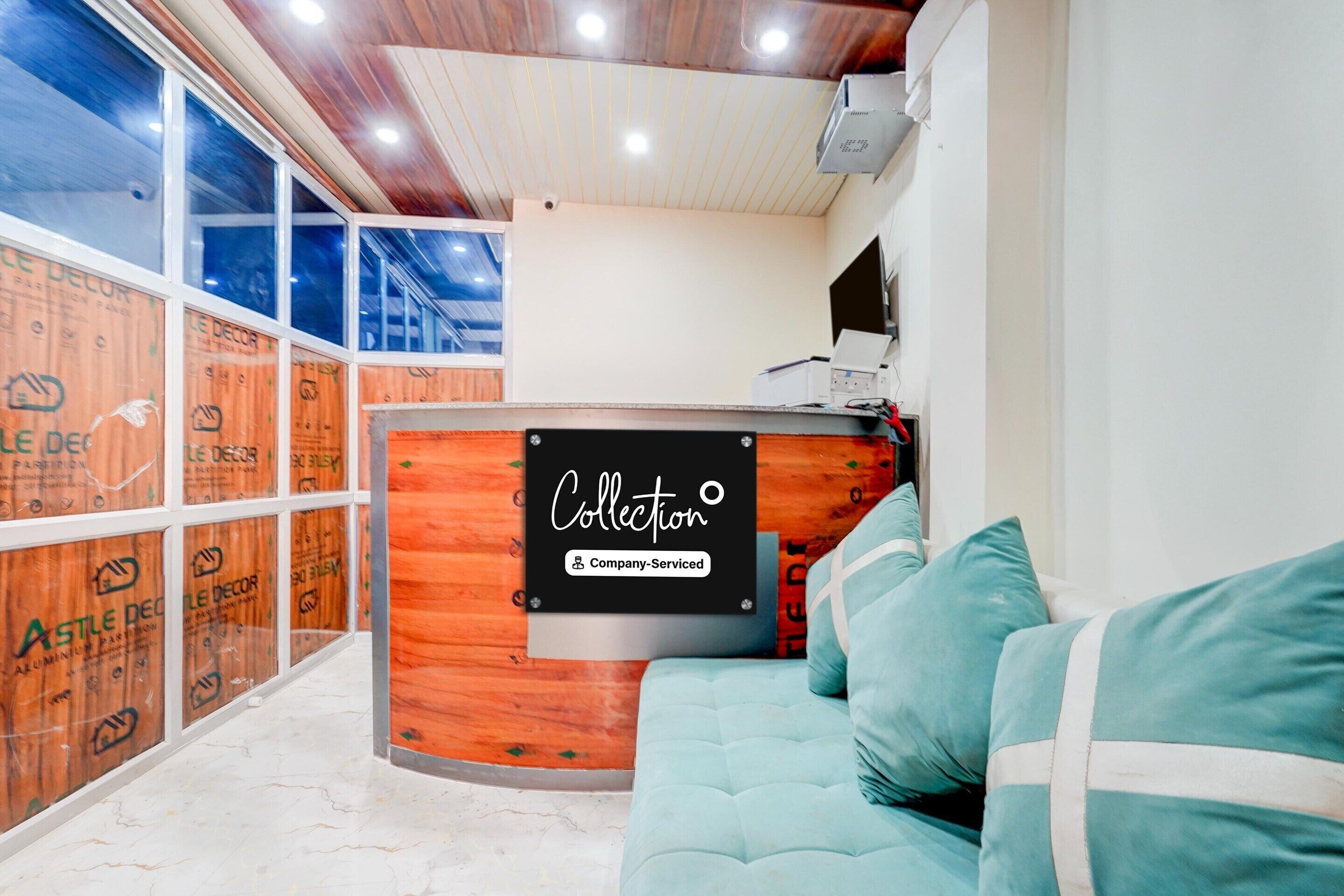 A reception area with a wooden reception desk, a teal sofa, and a view through large windows.