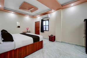 A bedroom with a bed, bedside table, and a small desk with a chair.