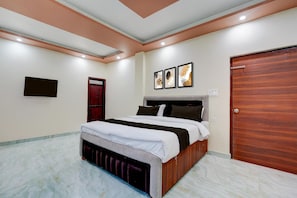 Un dormitorio con una cama, una puerta de madera y tres cuadros en la pared.
