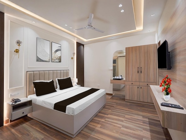 A modern hotel room with a large bed, bedside tables, a wardrobe, and a TV mounted on the wall.