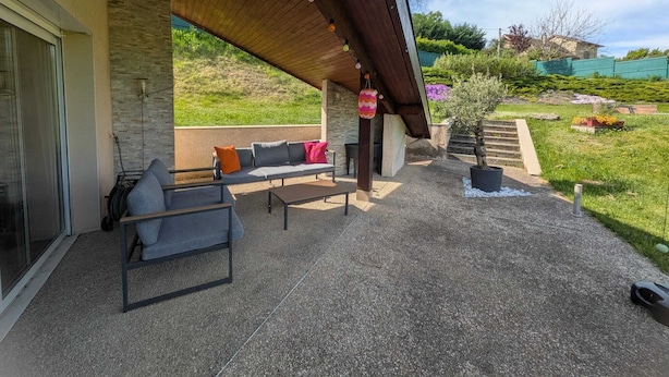 Une terrasse extérieure avec un canapé, une table et une décoration suspendue.