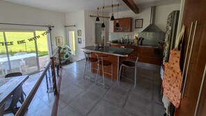 Une cuisine moderne dotée d’un grand îlot central, de tabourets de bar et offrant une vue sur l’extérieur.