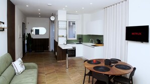 Ein moderner Wohnbereich mit Essplatz, Küchenzeile und einem an der Wand befestigten Flachbildfernseher.