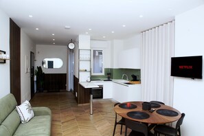 Ein moderner Wohnbereich mit Essplatz, Küchenzeile und einem an der Wand befestigten Flachbildfernseher.