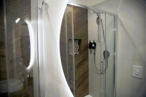 Ein modernes Badezimmer mit Duschkabine aus Glas, einem weißen Waschbecken und einer dekorativen Wandverkleidung.
