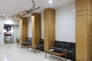 A lobby with a reception desk, two sofas, and a coffee table. - Hotel Kohinoor Plaza - Anhs (Chhatrapati Sambhajinagar)