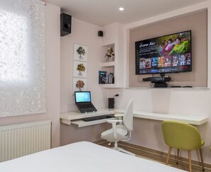 A modern room with a desk, a laptop, a TV mounted on the wall, and a chair. - 34m² studio — 90m from the beach in Chania —Self Check‑in, balcony, Fast WiFi (Chania)