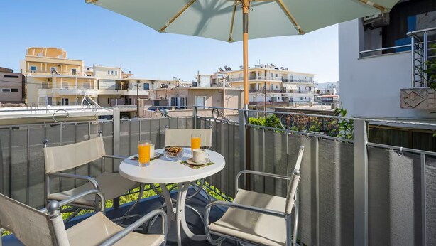 Un balcone con tavolo, sedie e ombrellone.