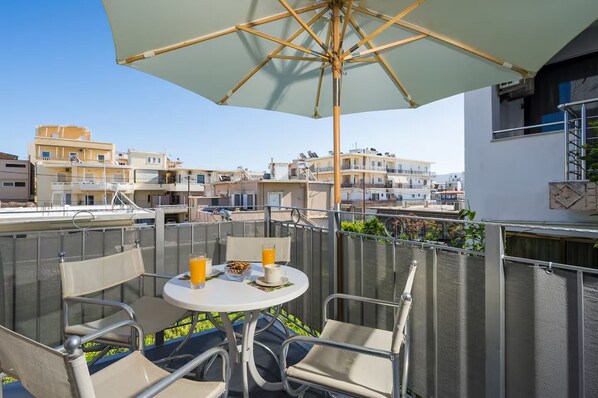 A balcony with a table, chairs, and an umbrella. - 34m² studio — 90m from the beach in Chania —Self Check‑in, balcony, Fast WiFi (Chania)