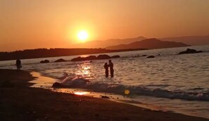 A sunset over a body of water with rocks and a distant mountain range. - 34m² studio — 90m from the beach in Chania —Self Check‑in, balcony, Fast WiFi (Chania)