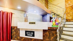 Mostrador de recepción de hotel con un letrero que dice 'RECEPTION', un letrero que dice 'HOTEL' y una escalera con barandilla.