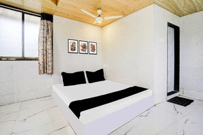 A bedroom with a bed, a ceiling fan, a window with curtains, and framed pictures on the wall.