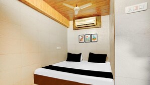 Un dormitorio con cama, ventilador de techo, aire acondicionado y una obra de arte colgada en la pared.
