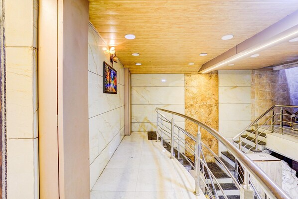 A modern interior with marble walls, a wooden ceiling, and a staircase with metal railings.