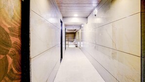 Un pasillo con paredes de mármol y suelo de baldosas, que conduce a una puerta al final.