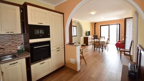 A kitchen with built-in appliances, an archway leading to a dining area, and a living room with a fireplace. - In the Peaceful Hillside Village of Aurano (Aurano)